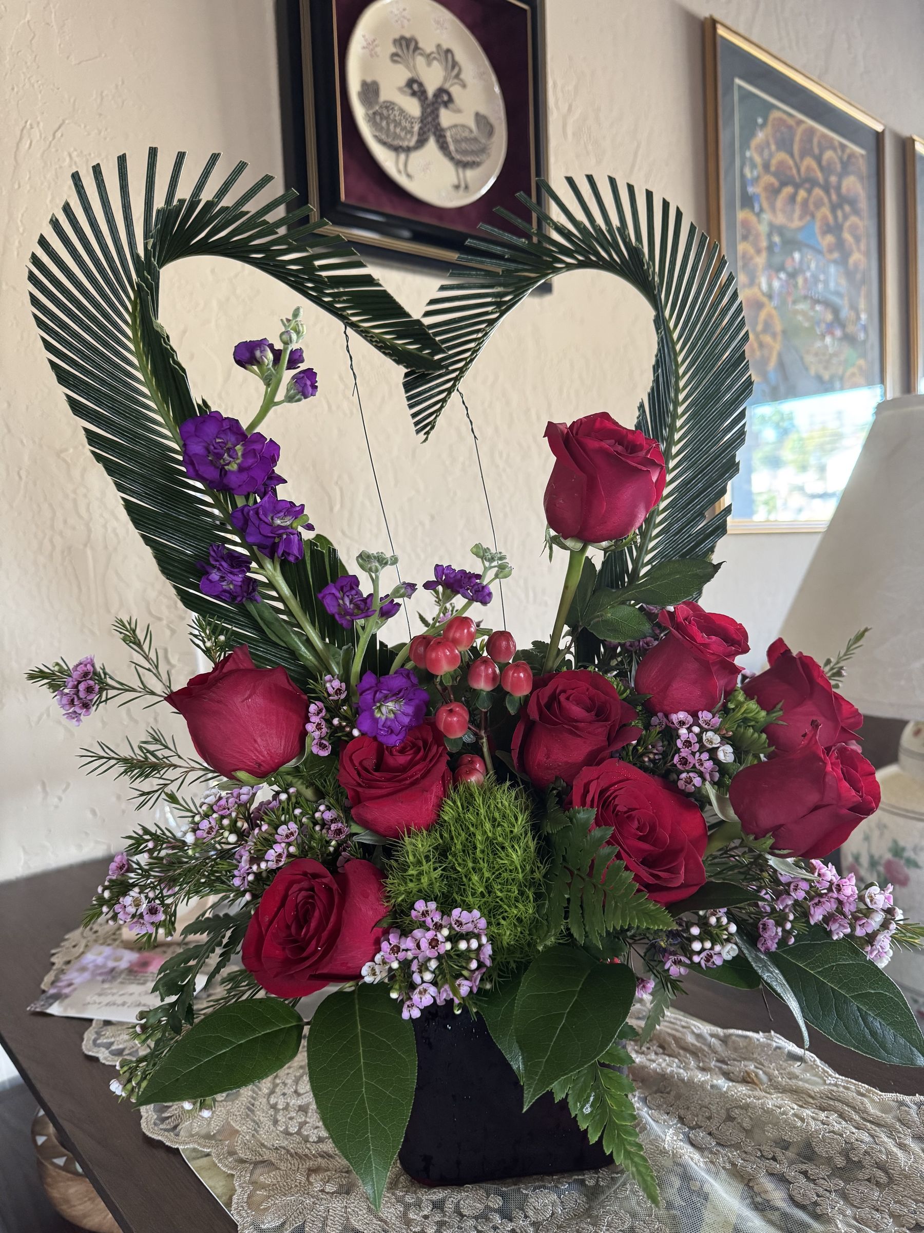 Heart-shaped rose arrangement framed with palm fronds